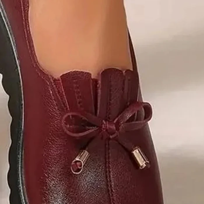 Primo piano del fiocco in pelle bordeaux con i due puntali dorati